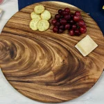 Round walnut charcuterie board displaying artisan cheeses and fruit